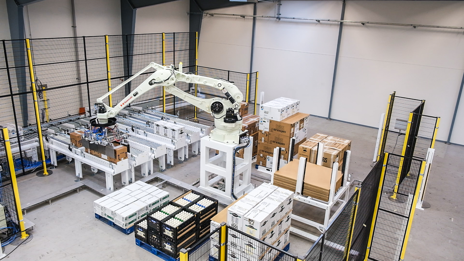 Automated palletizing robot organizing cases and cartons onto pallets within a fenced SANOVO palletizing system.