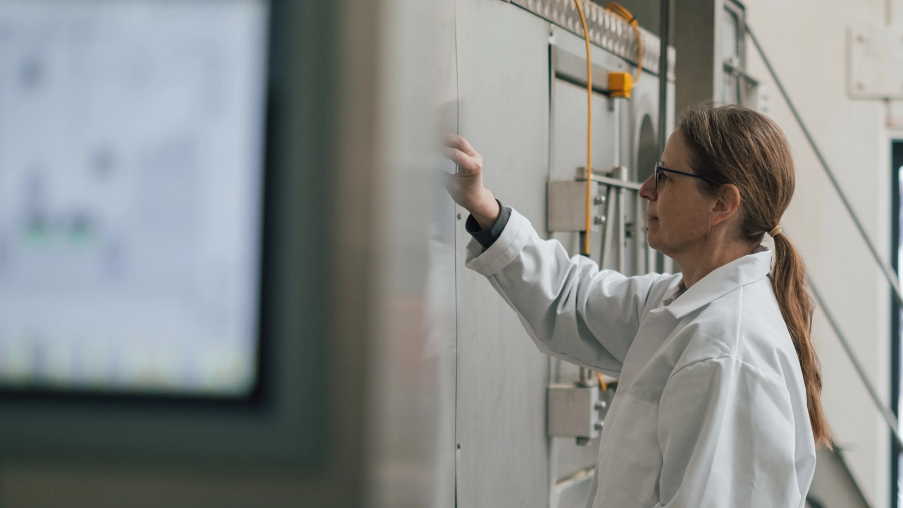 Staff member overseeing spray drying process on production equipment.
