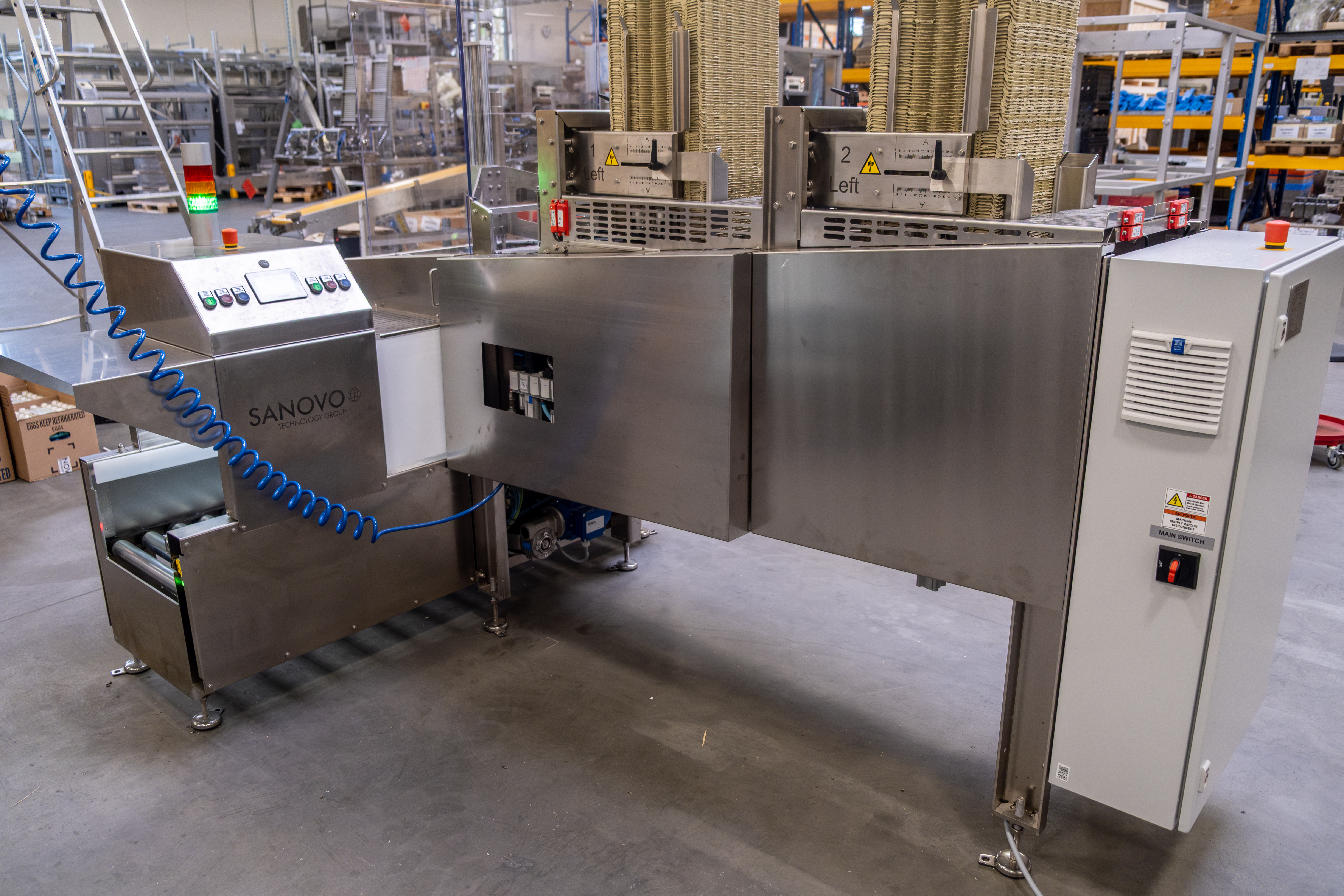 SANOVO Top Tray Denester operating in a facility, automating top tray application on full and half egg cases.