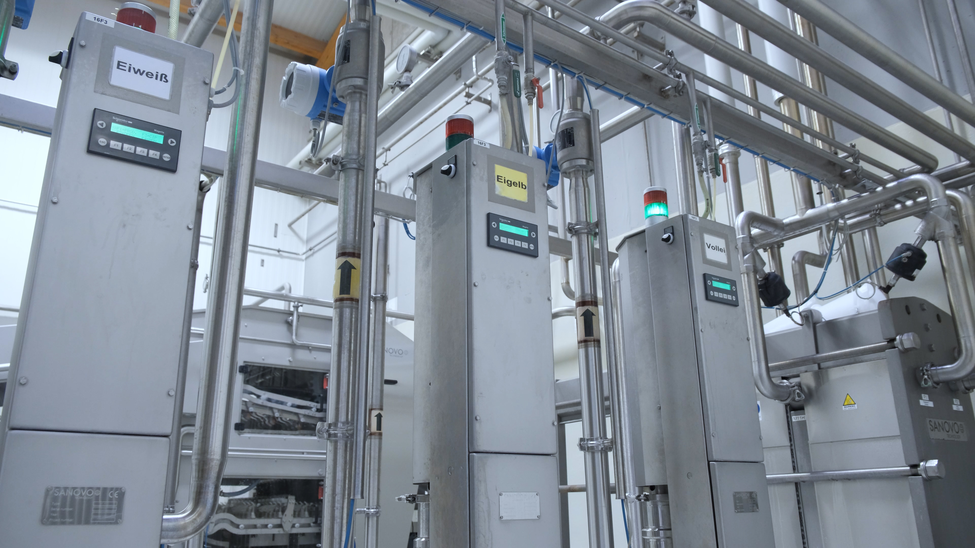 SANOVO automatic liquid egg filtration units with control panels in an egg processing line.
