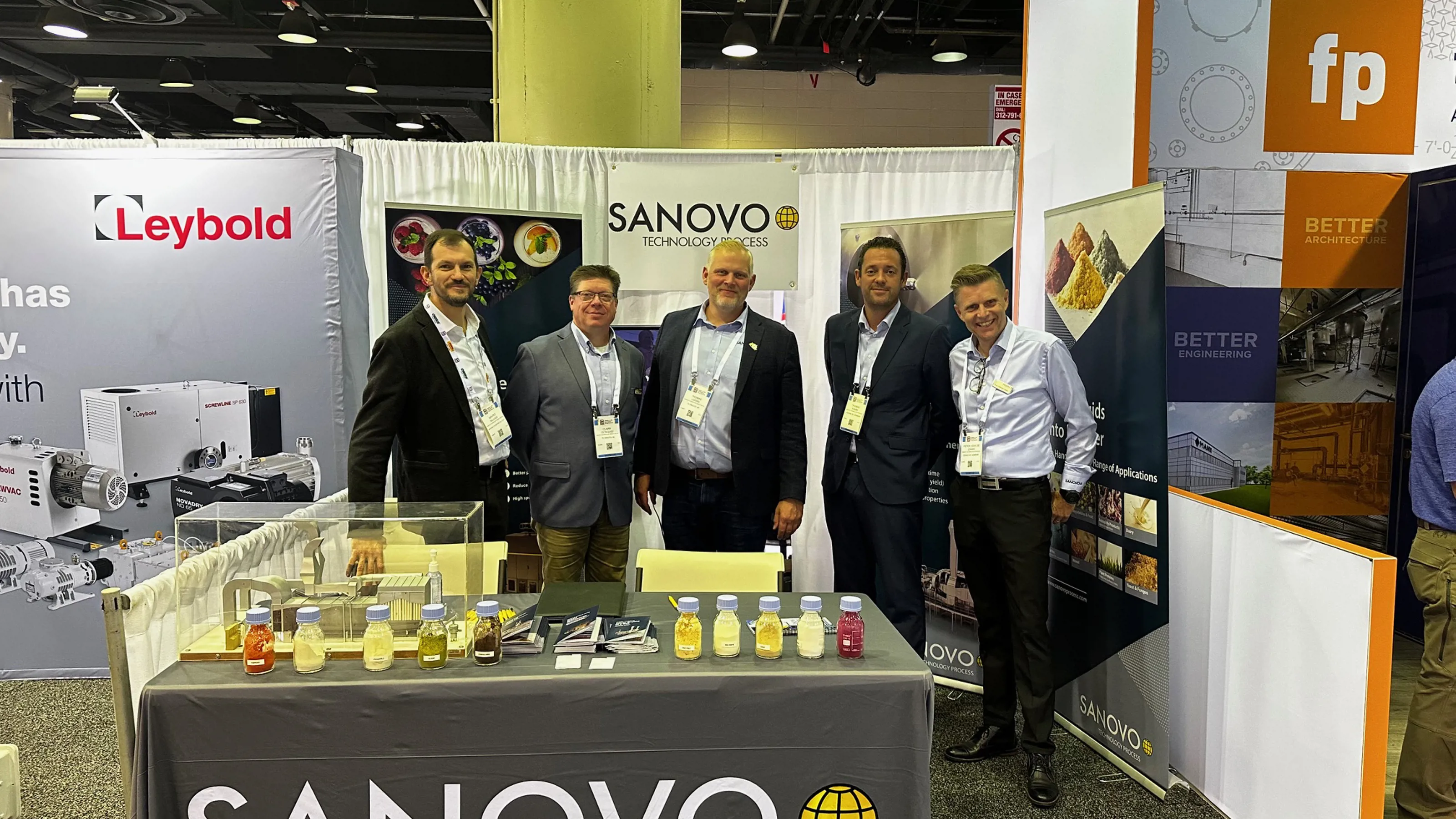 SANOVO TECHNOLOGY PROCESS team standing in front of a table at an exhibition