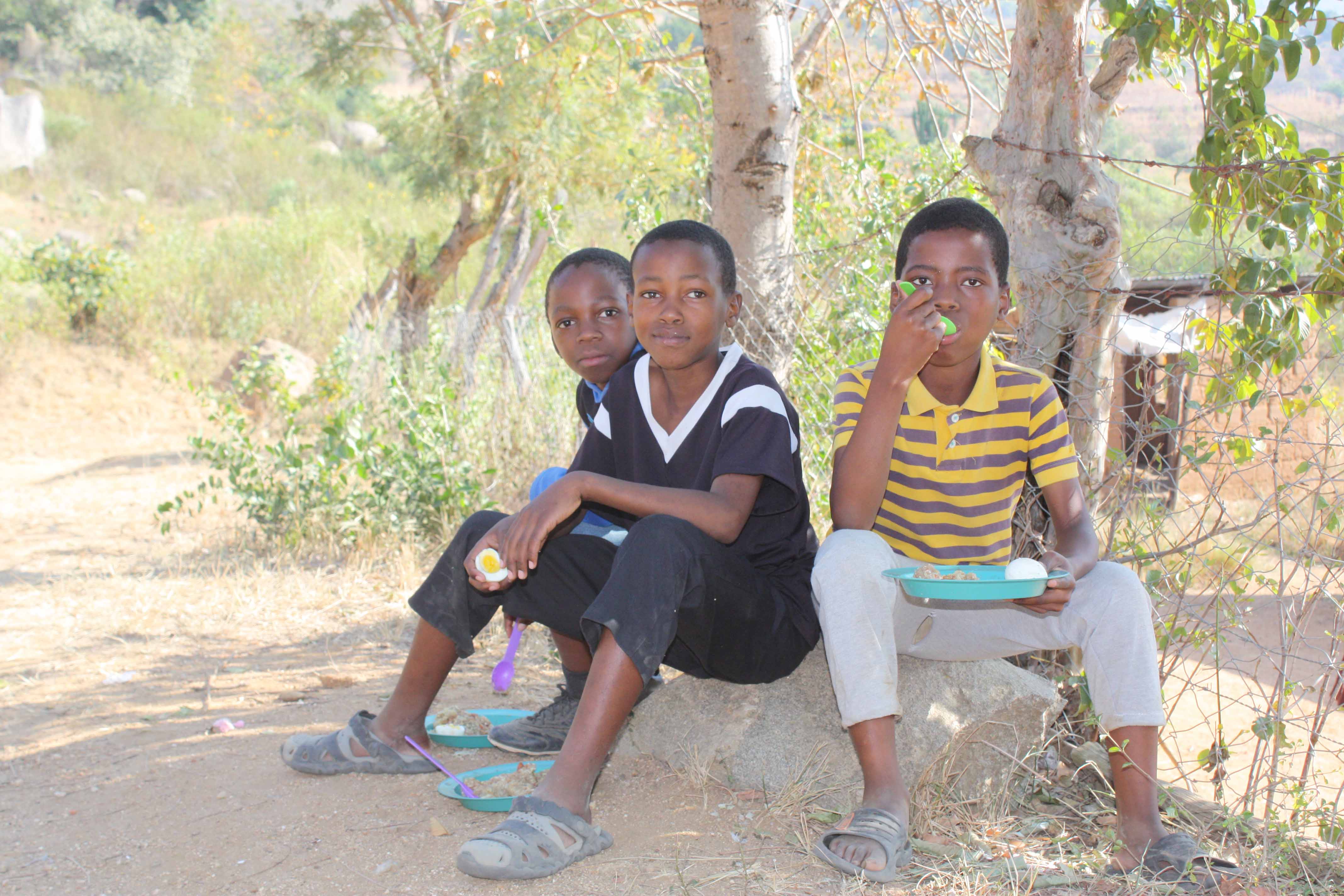 Local children eating eggs provided.