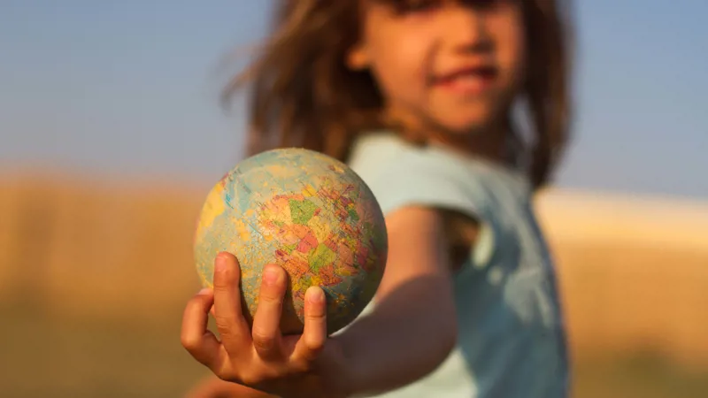 Symbolic image of responsibility and care for the world with child holding a globe