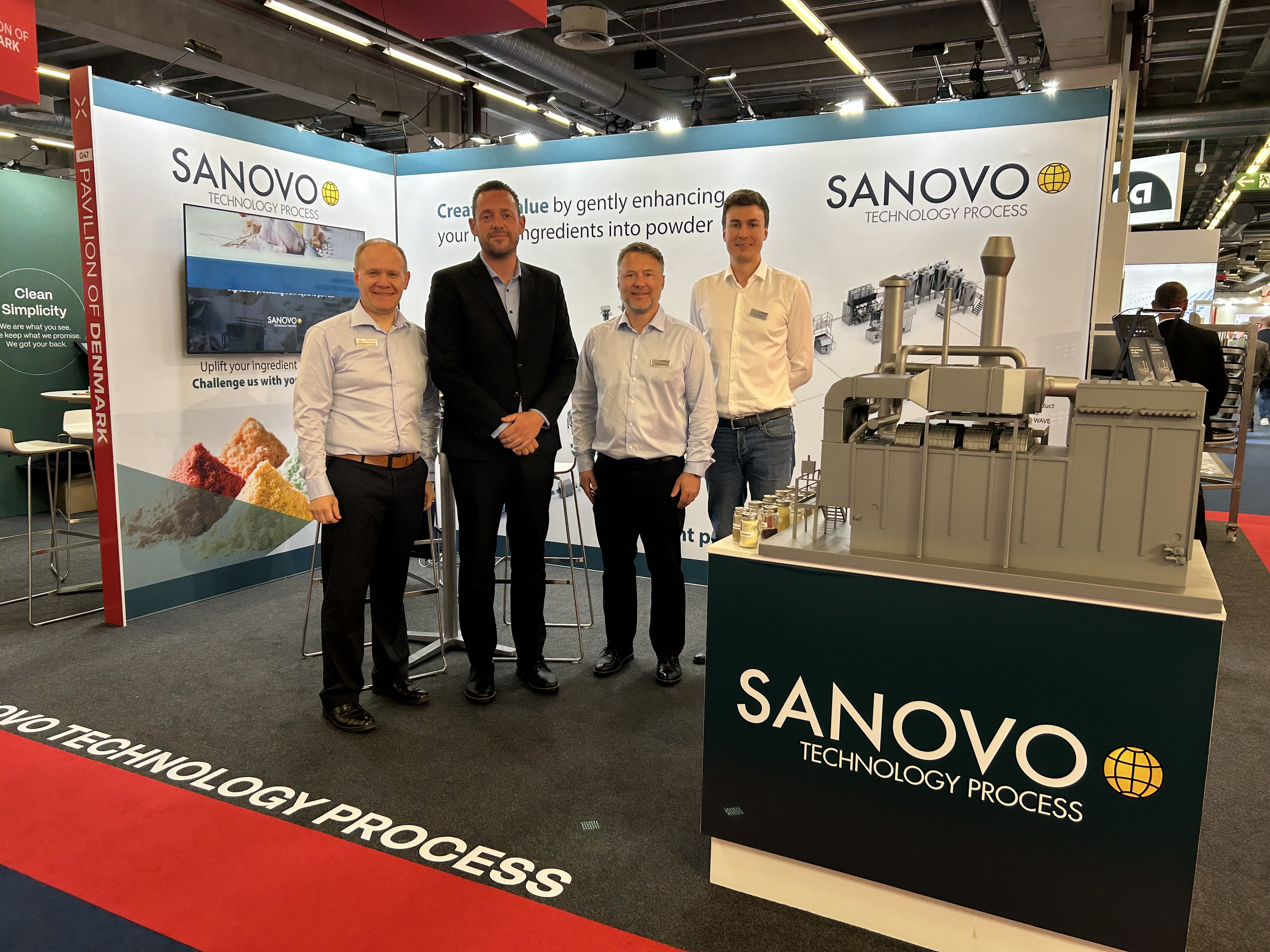 SANOVO TECHNOLOGY PROCESS team at a trade show booth presenting spray drying and powder processing solutions.