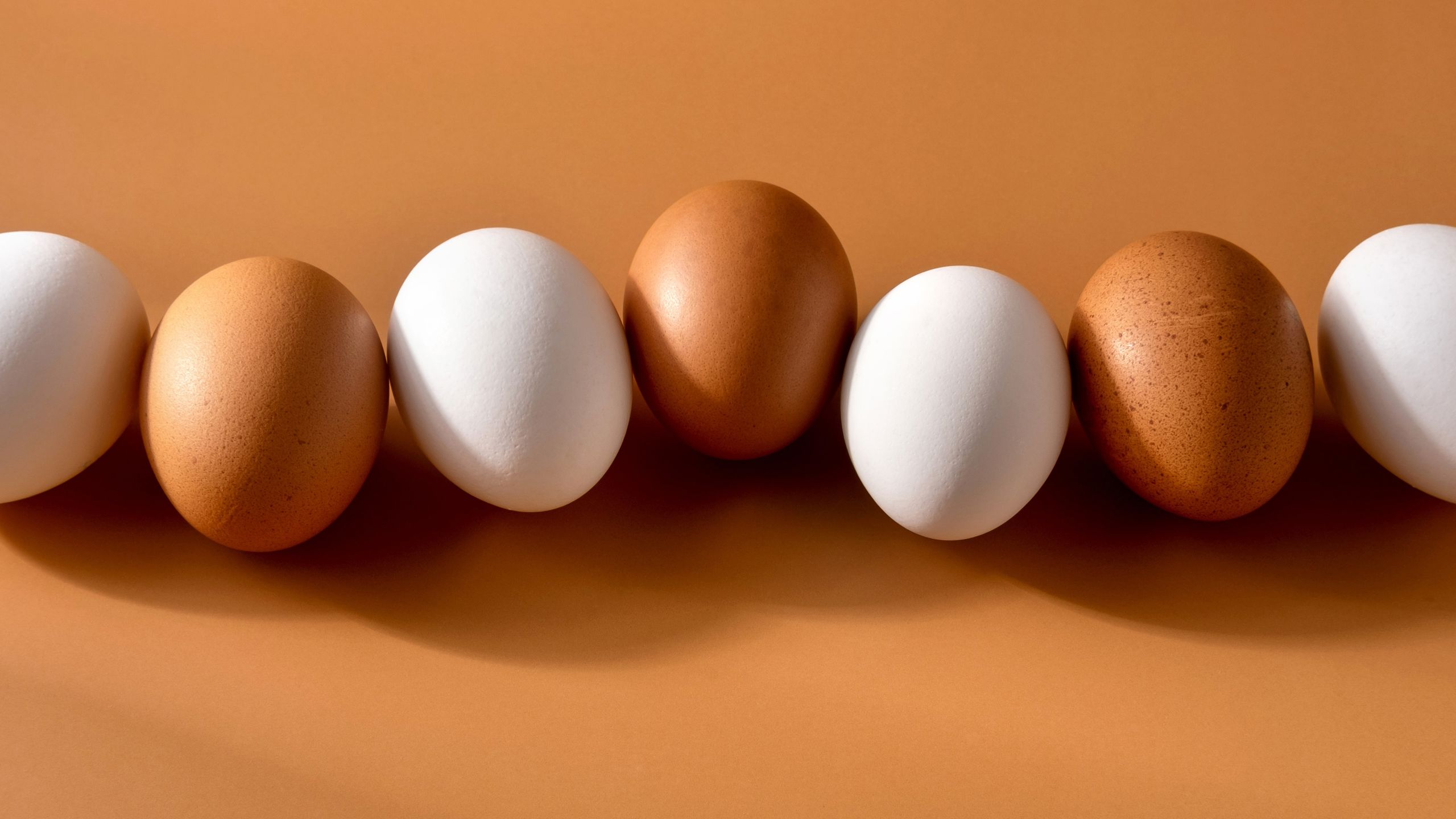 Brown and white eggs lined up in a row next to each other.
