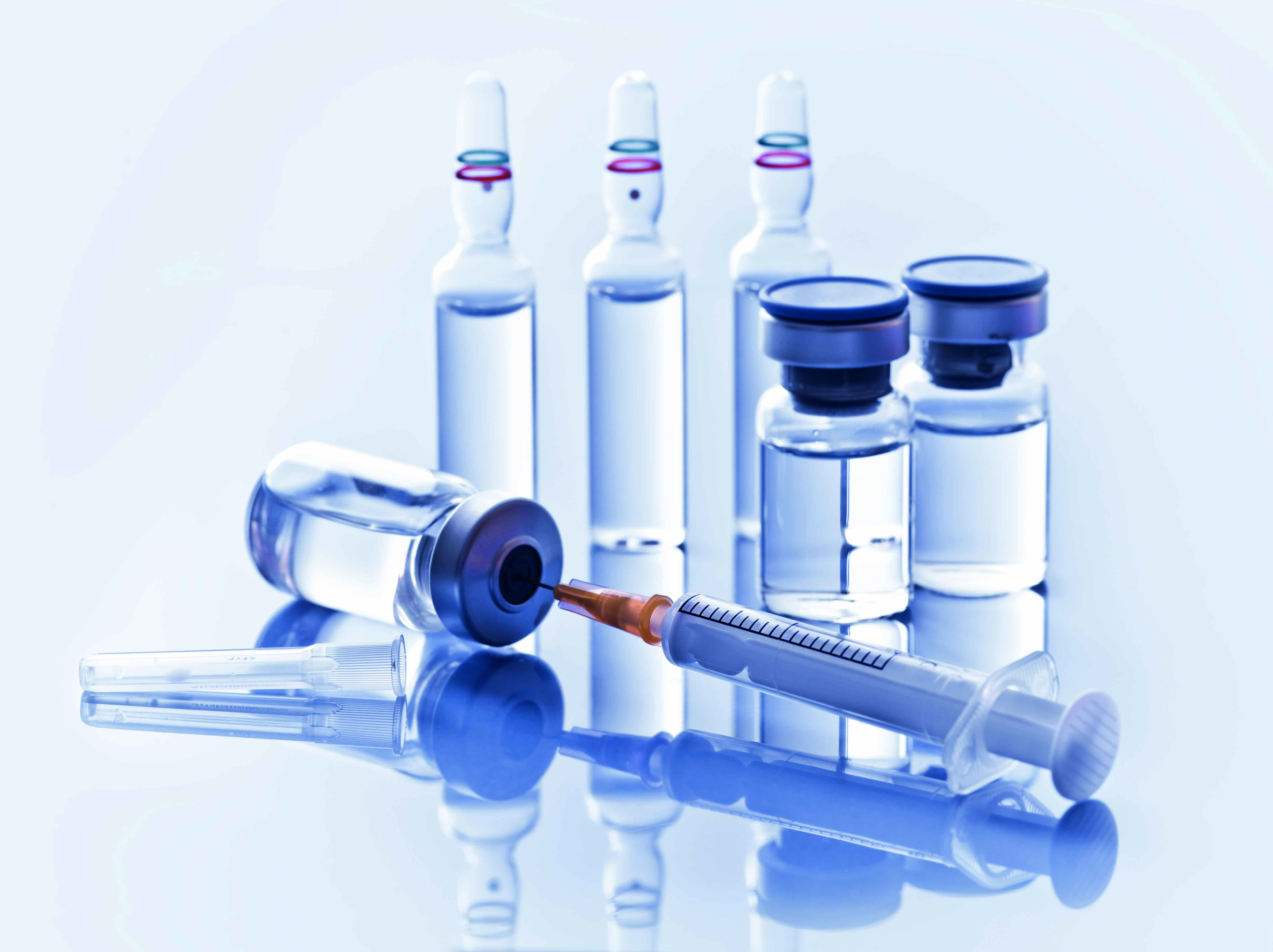 Vaccine vials and ampoules with syringe used in vaccine production and laboratory environments.