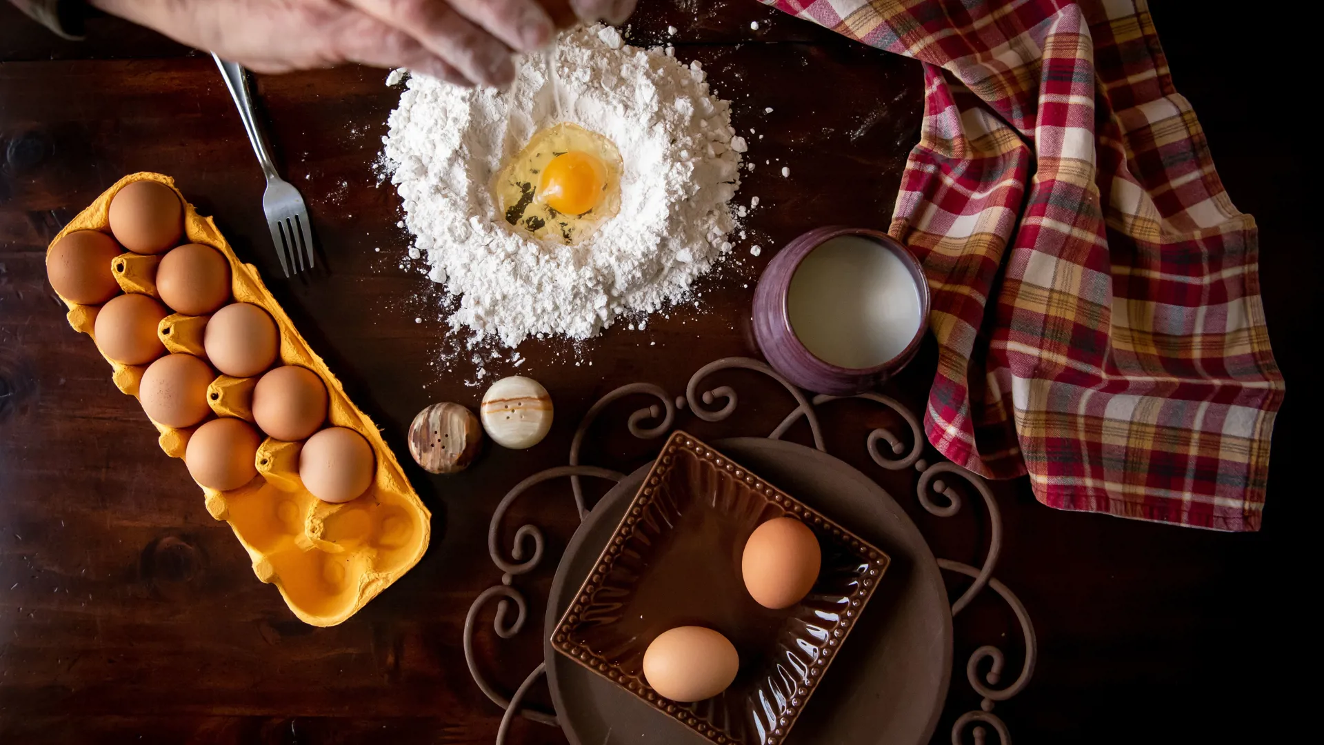 Person preparing a meal at a kitchen table with eggs
