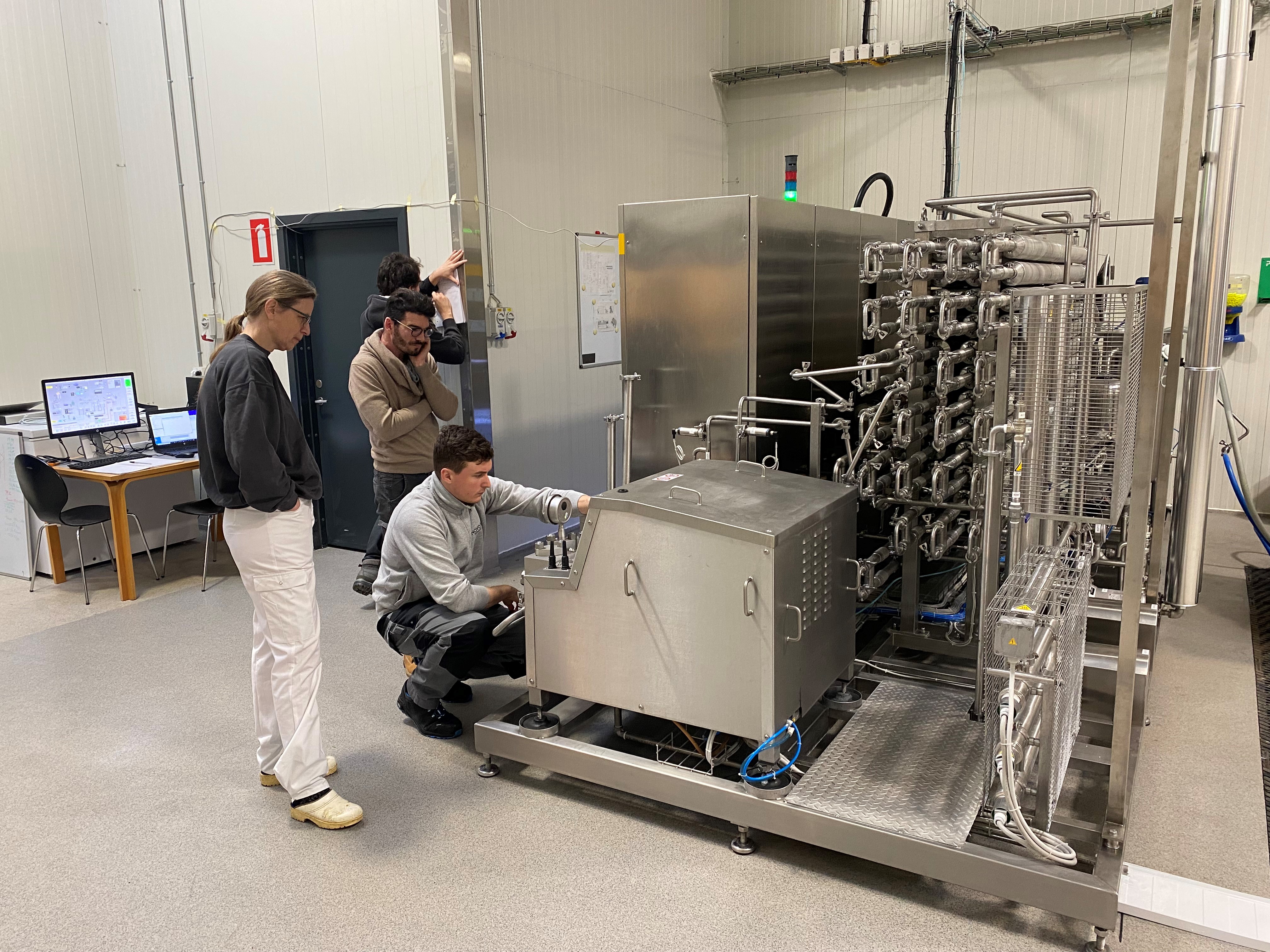 Technicians performing hands-on training on SANOVO WAVE pasteurization equipment.