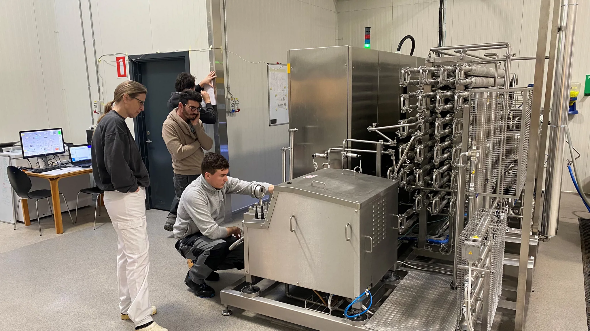 Technicians performing hands-on training on SANOVO WAVE pasteurization equipment.