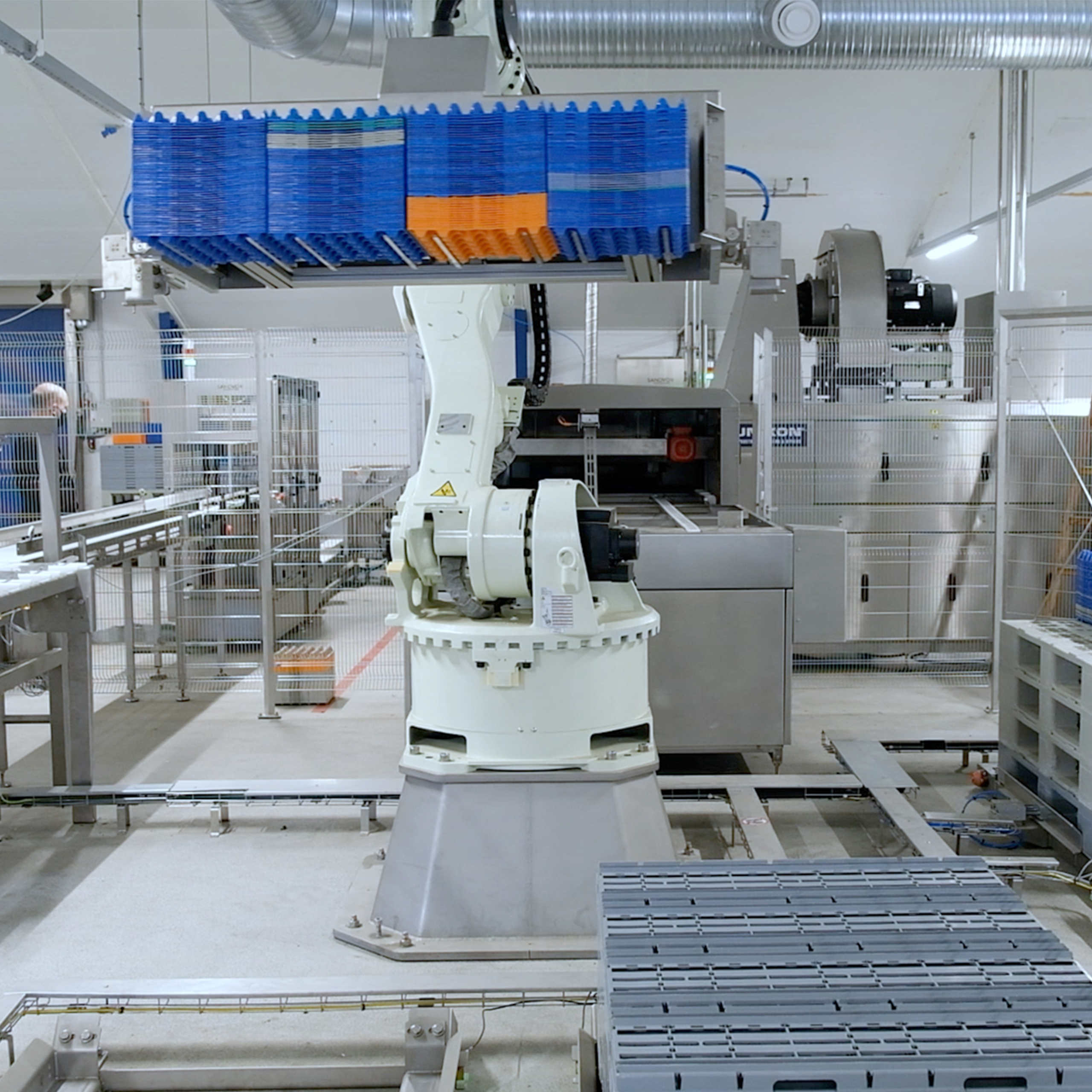 SANOVO robotic system lifting stacked plastic trays for automated pallet and interlayer handling in a facility.