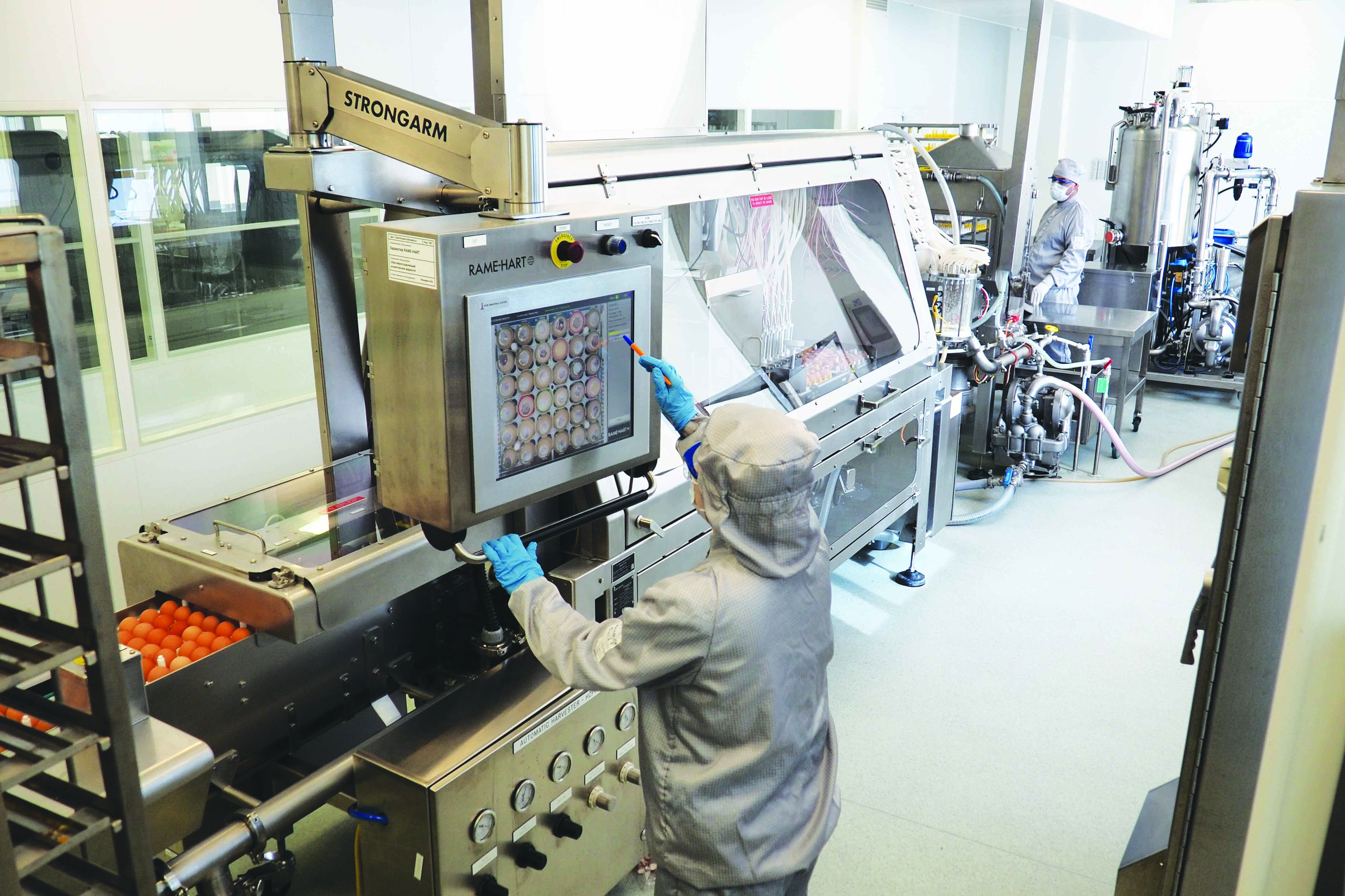 Operator monitoring a RAME-HART harvester system during automated egg inoculation and harvesting.