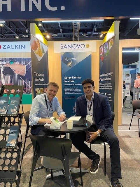 SANOVO TECHNOLOGY PROCESS exhibition booth with team members discussing spray drying solutions at an industry trade show.